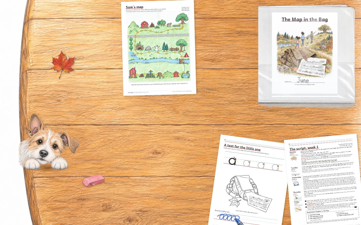 The whole Friday on the table from above: Sam's map coloured in, Teddy's crayon test, the closed binder with the book's cover, The Map in the Bag, written by June, and Biscuit at the edge.